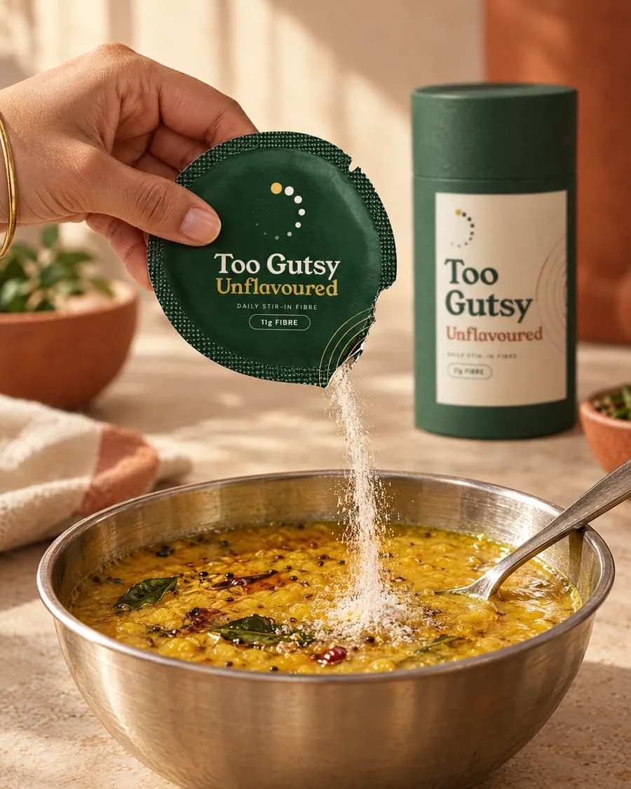 A round green sachet of Too Gutsy Unflavoured being poured into a bowl of dal